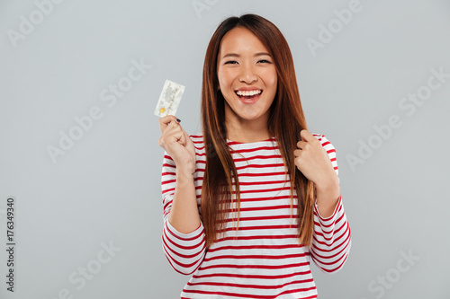 Asian happy lady standing isolated over grey wall © Drobot Dean