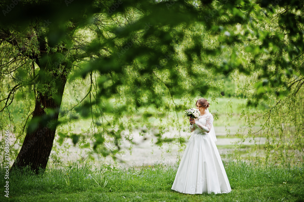 Portrait of a beautiful young bride posing with a bouquet outdoor on her own. Portrait of a beautiful young bride posing with a bouquet outdoor on her own.