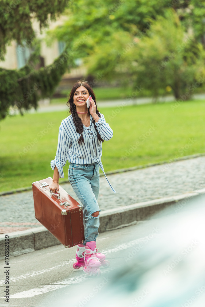 Naklejka premium girl in roller skates with smartphone and suitcase