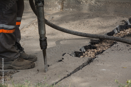 Road repairing works with jackhammer. Male worker using jackhammer pneumatic drill machinery on road repair.