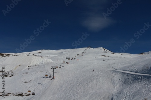 Chairlift over the ski slope against blue sky (Watles, Bozen, Italy) photo