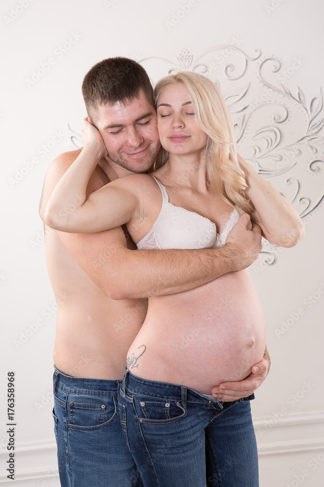 Beautiful pregnant couple in love on the background. Hands of husband on the tummy of his pregnant wife. Young man tenderly stroked pregnant belly of his wife. Husband kissing pregnant belly. Beautiful pregnant couple in love on the background. Hands of husband on the tummy of his pregnant wife. Young man tenderly stroked pregnant belly of his wife. Husband kissing pregnant belly.