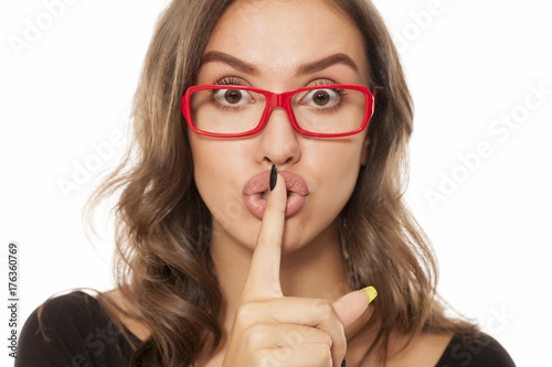 Portrait of beautiful young woman with glasses showing silent sign on white background