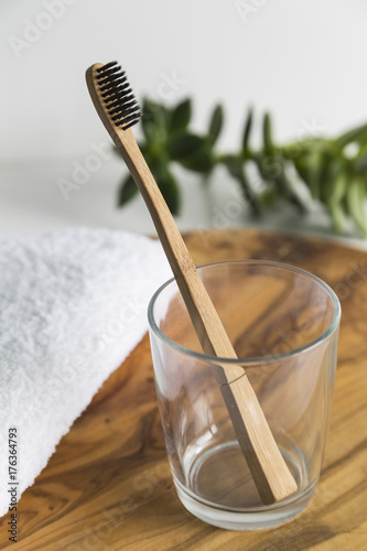 Bamboo toothbrush in a glass with white towel