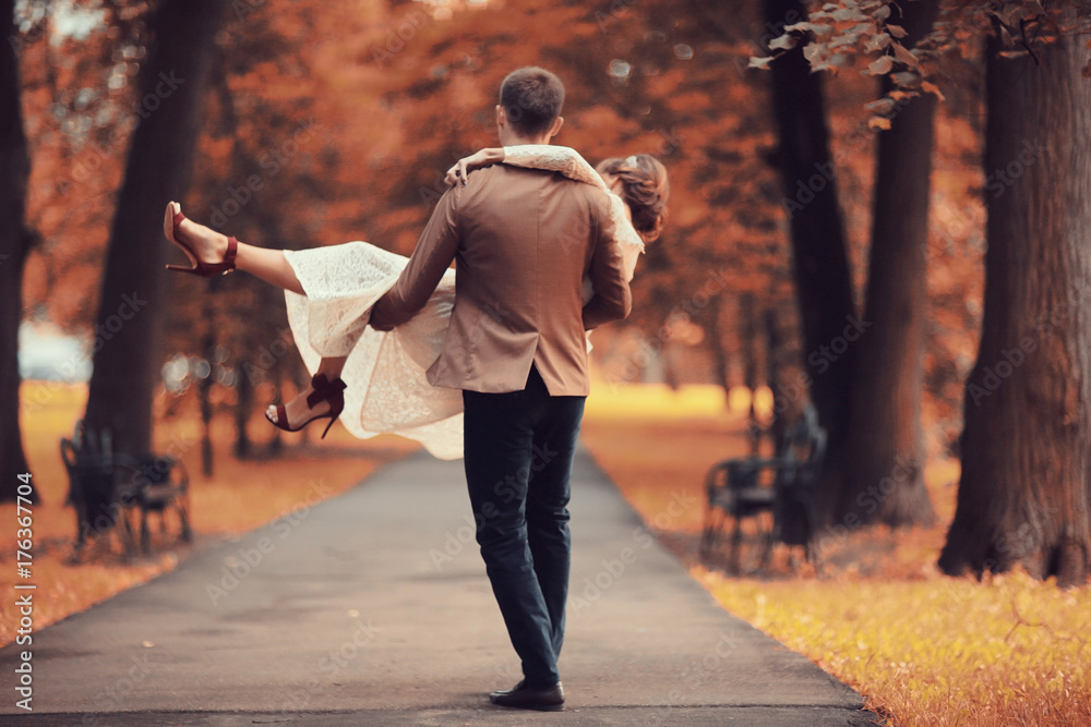 Obraz premium Newlyweds groom and bride walking in autumn park