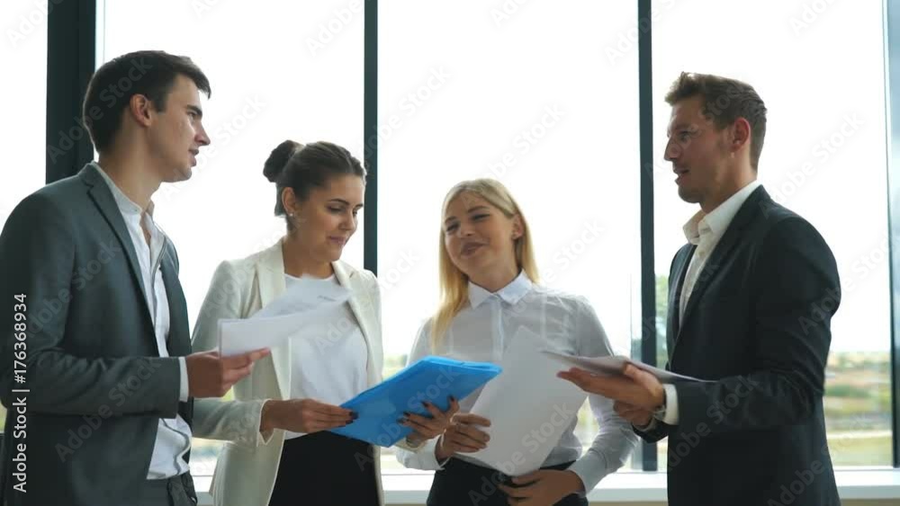 Confident business people discussing project while standing in office Confident business people discussing project while standing in office