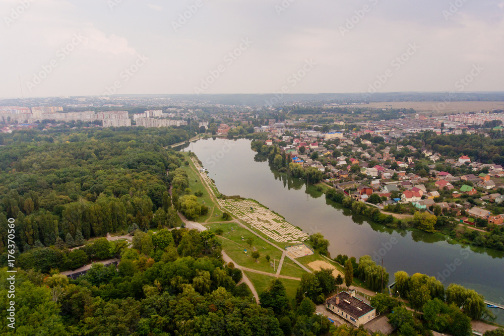Obraz premium Arial view of a beautiful landscape of a park, a city and a lake.