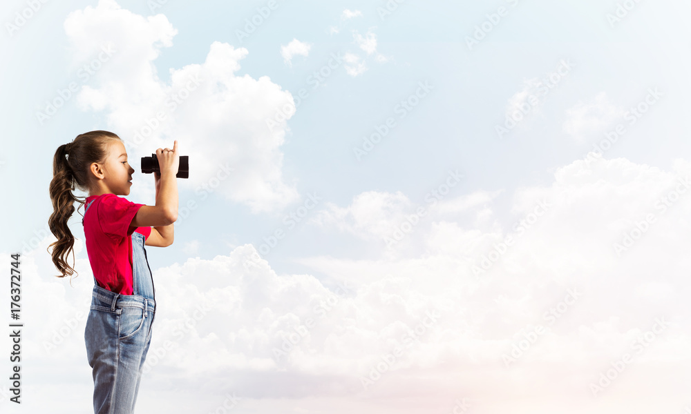 Concept of careless happy childhood with girl looking in binoculars Concept of careless happy childhood with girl looking in binoculars