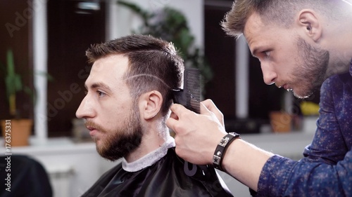 Male barber and customer. Hairdresser making the hairstyle with clipper. Scene from barber shop © kustvideo