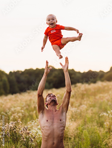 Dad throws his son up standing on the field