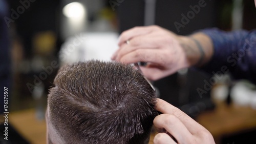 Making hairstyle with scissors and comb. Hairdresser at work. Male customer and barber. Close up view