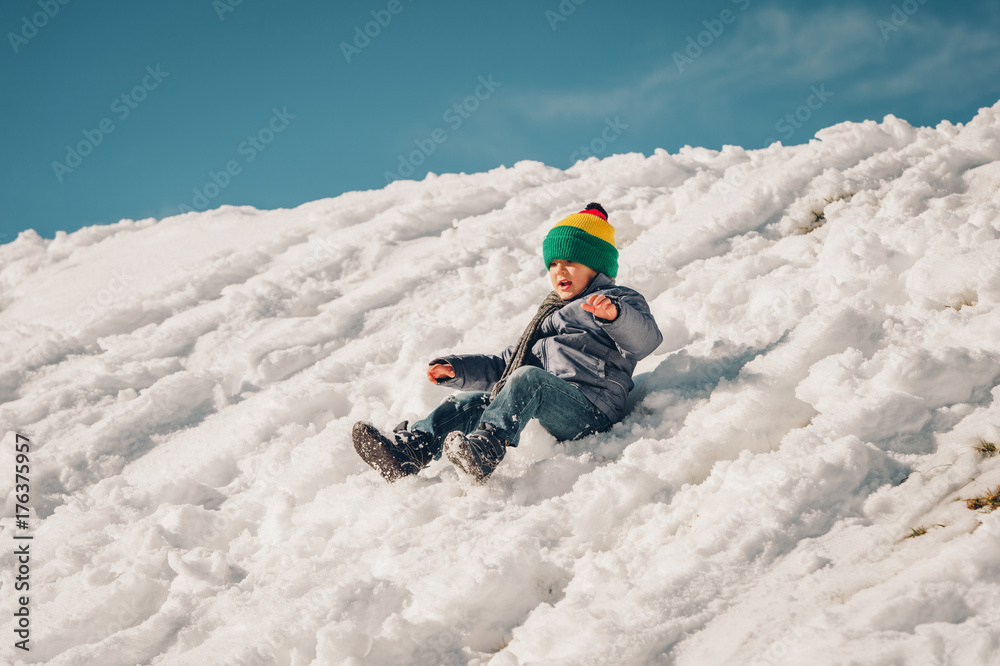 Little boy climbing the snow hill, winter vacation with children. Image taken in Valais, Switzerland