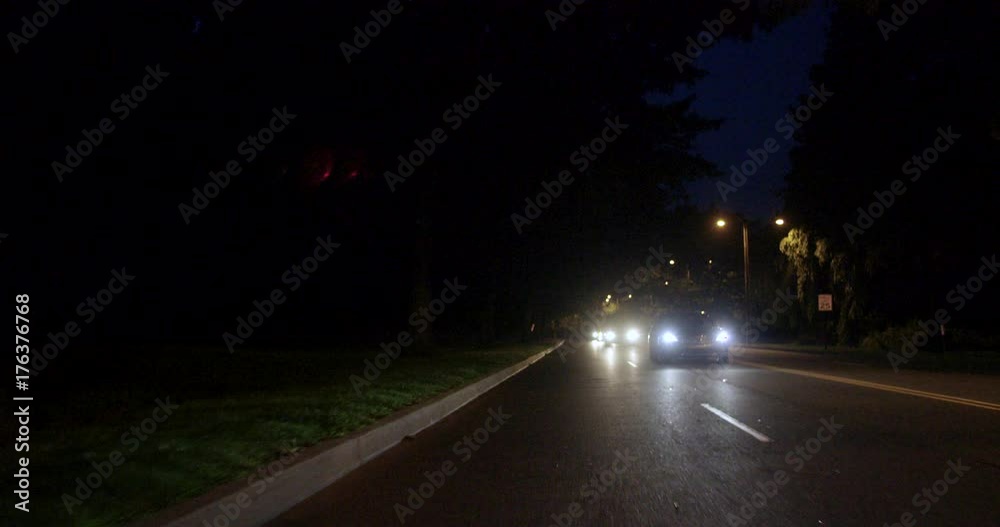 Cars driving on a dark street at night in an urban city, in slow motion Cars driving on a dark street at night in an urban city, in slow motion