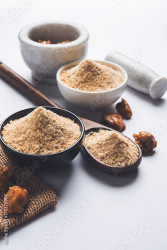 Asafoetida cake and powder or Hing or Heeng which is an important ingredient in Indian food recipes with big wooden spoon and mortar, selective focus photo