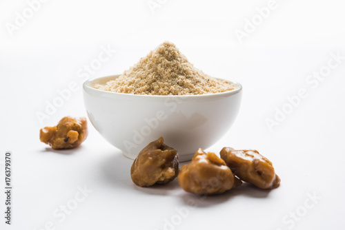 Asafoetida cake and powder or Hing or Heeng which is an important ingredient in Indian food recipes with big wooden spoon and mortar, selective focus photo