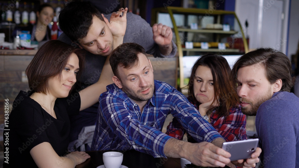 Attractive guys and girls in the cafe, do selfie on the phone. A company of friends is photographed together for social networks. Students of designers have a day off Attractive guys and girls in the cafe, do selfie on the phone. A company of friends is photographed together for social networks. Students of designers have a day off