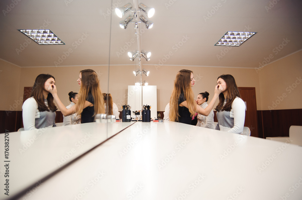 Make-up artist doing professional make-up of young woman
