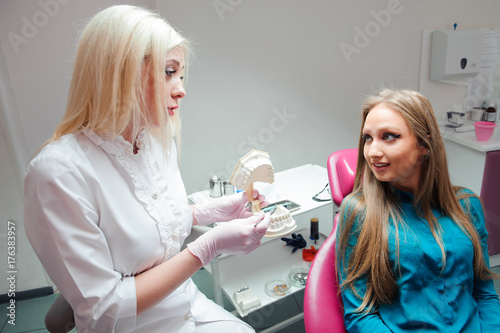 female dentist talking with female patient. Dentist holding a model in his hand