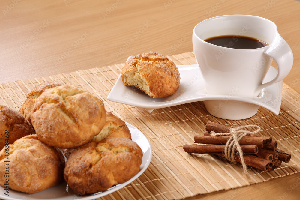 Traditional bulgarian cookies, called kurabiiki, cup of coffee and tied cinnamon sticks. Shallow depth of field, selective focus on the coffee mug and the bitten cookie. Space for text