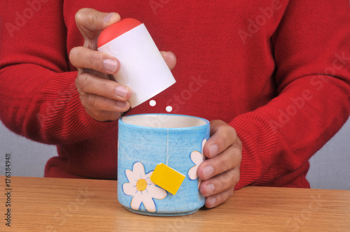 Tableau sur toile Personne mettant des sucrettes dans sa tasse de thé