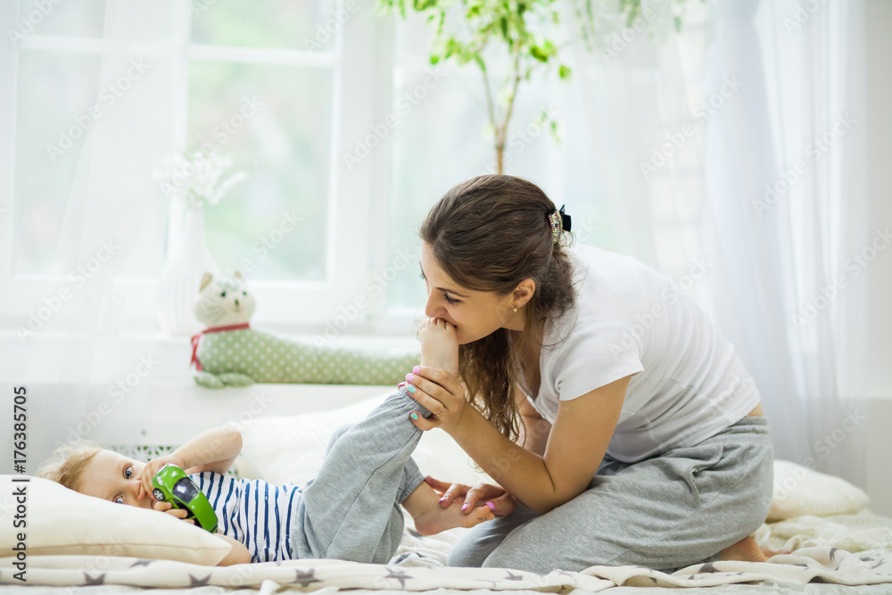 Young mother kissing her baby lying on the bed Young mother kissing her baby lying on the bed