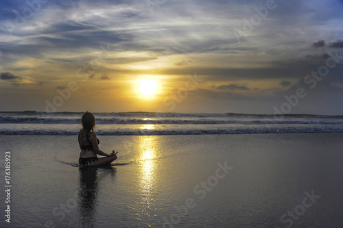 free woman sitting looking to sea sunset practicing yoga and meditation at beautiful Asian beach