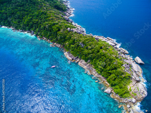 top aerial view of isolated tropical island with blue clear water and granite stones and speedboat above coral reef. Similan Islands, Thailand.