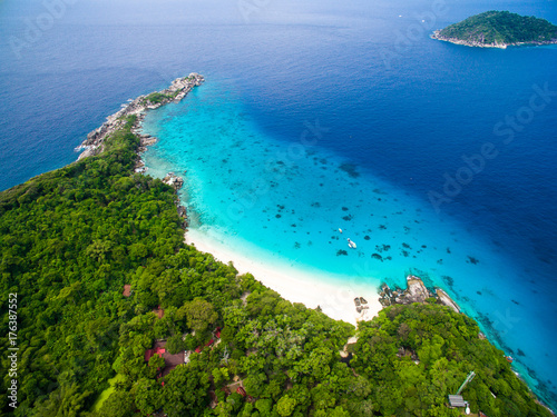 Top aerial view of isolated beautiful tropical island with white sand beach, blue clear water and granite stones. Also top view of speedboats above coral reef. Similan Islands, Thailand. © Marina