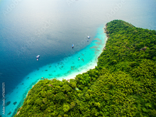 Top aerial view of isolated beautiful tropical island with white sand beach, blue clear water and granite stones. Also top view of speedboats above coral reef. Similan Islands, Thailand.