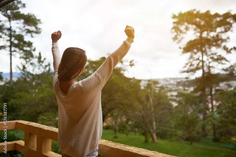 Young woman in sweater enjoying morning on balcony of resort hotel