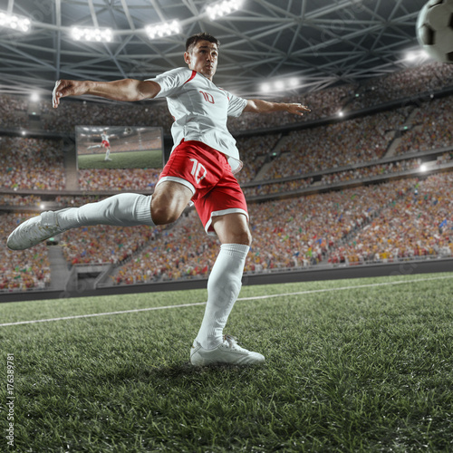 Soccer player performs an action play and beats the ball on a professional stadium. Player wears unbranded sport uniform. © Alex