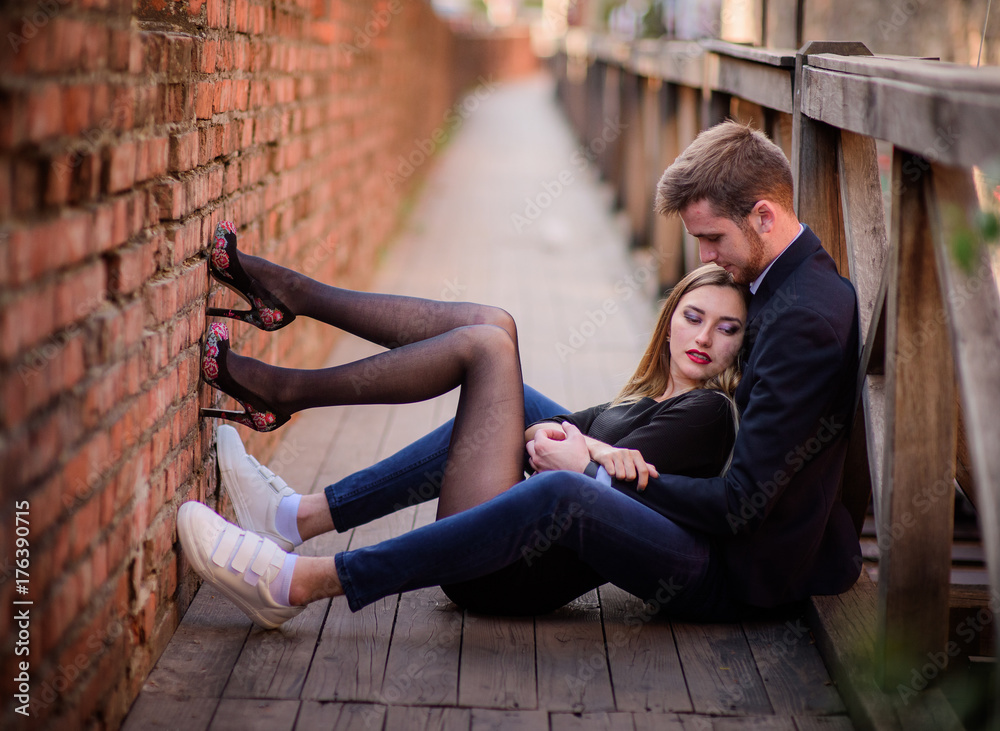 Man and woman sit together on a wooden bridge Man and woman sit together on a wooden bridge