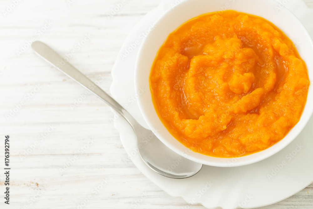 Pumpkin puree in a bowl with spoon on a white table Pumpkin puree in a bowl with spoon on a white table