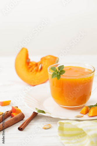 The juice of pumpkin in the bowl with the cinnamon and chopped pumpkin on white