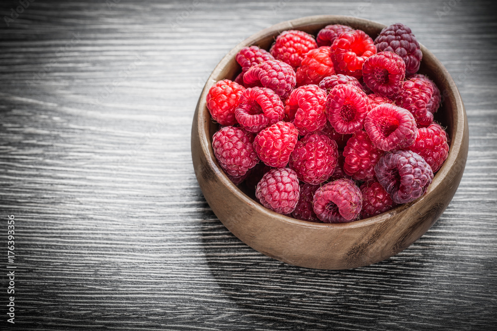 Bowl with red raspberries on wooden board Bowl with red raspberries on wooden board
