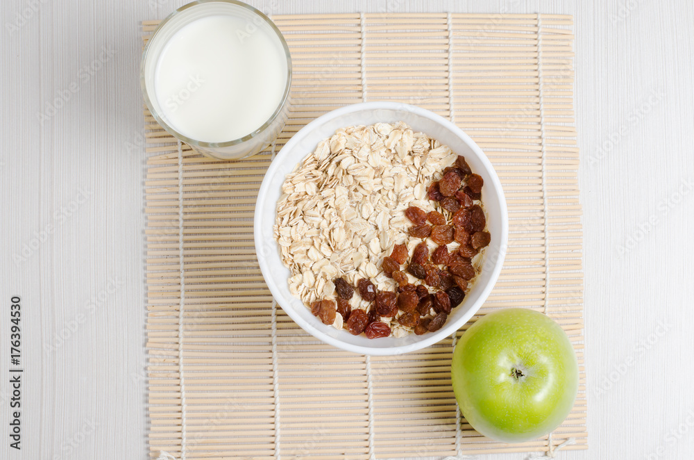 Oatmeal with raisins on the tablecloth from bamboo. Milk, green Apple Oatmeal with raisins on the tablecloth from bamboo. Milk, green Apple