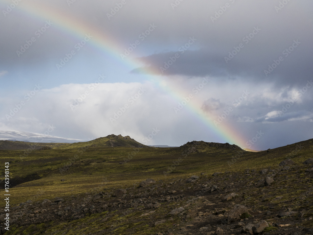 Rainbow over the mountains of Iceland, covered with green moss