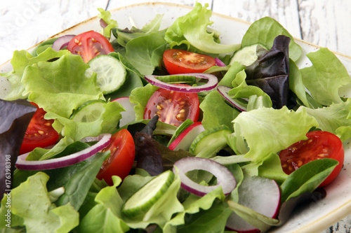 bowl of salad with vegetables and greens  with tomato  cucumber and onions