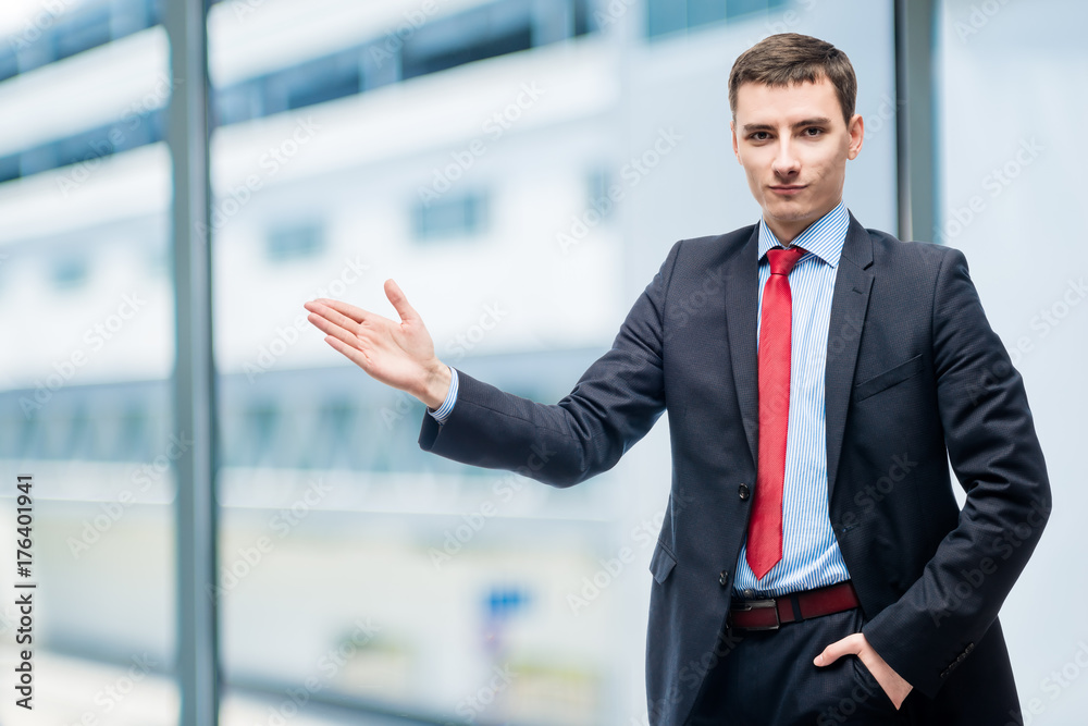 Young businessman showing his hand on something in office Young businessman showing his hand on something in office