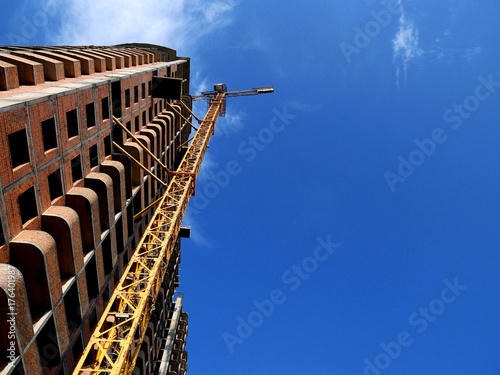 Construction crane near building on blue sky background.