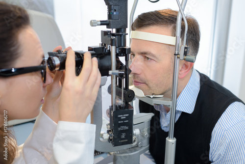 young female ophthalmologist and male patient checking eyesight photo