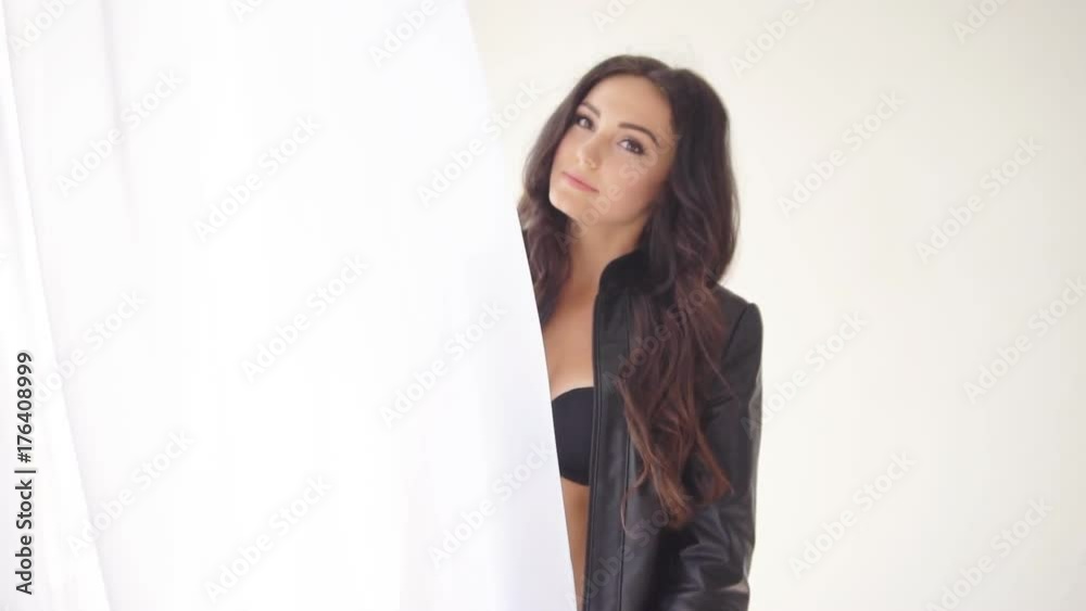 brunette girl stands at the window with the curtain