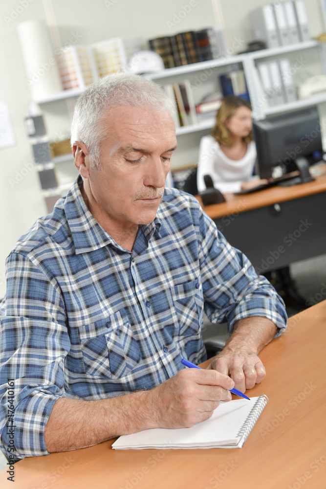 Senior office worker taking notes
