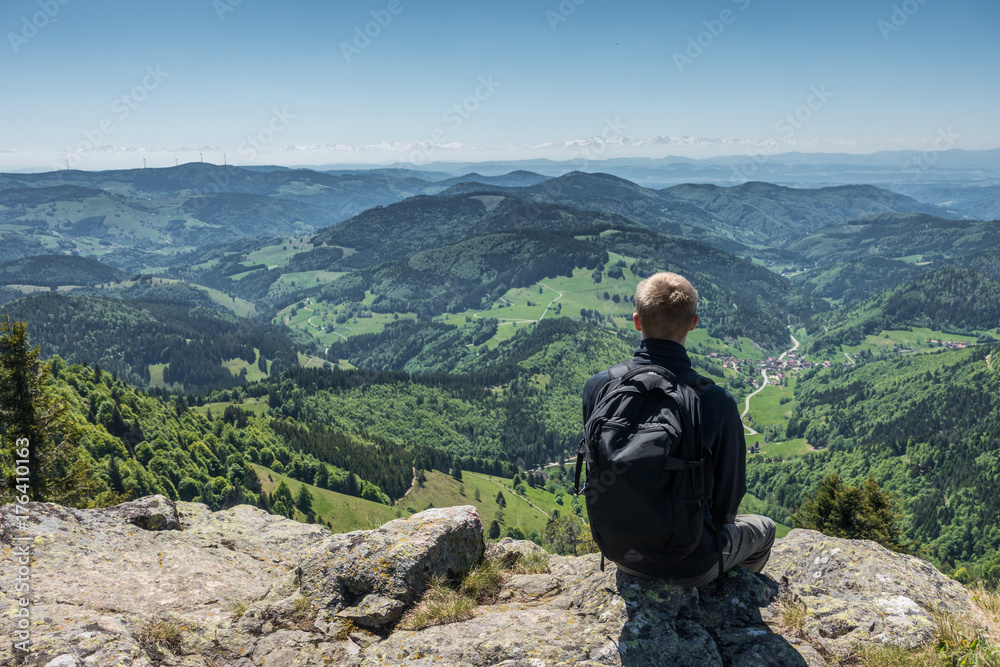 Photography of man sitting on cliff edge