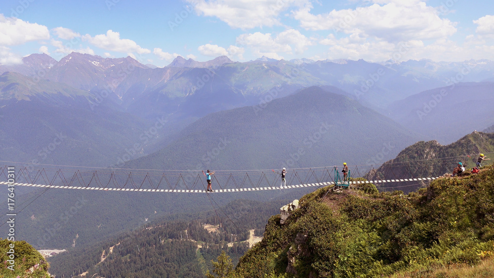The crossing of the abyss in the mountains .People go on rope bridge across the chasm. The crossing of the abyss in the mountains .People go on rope bridge across the chasm.