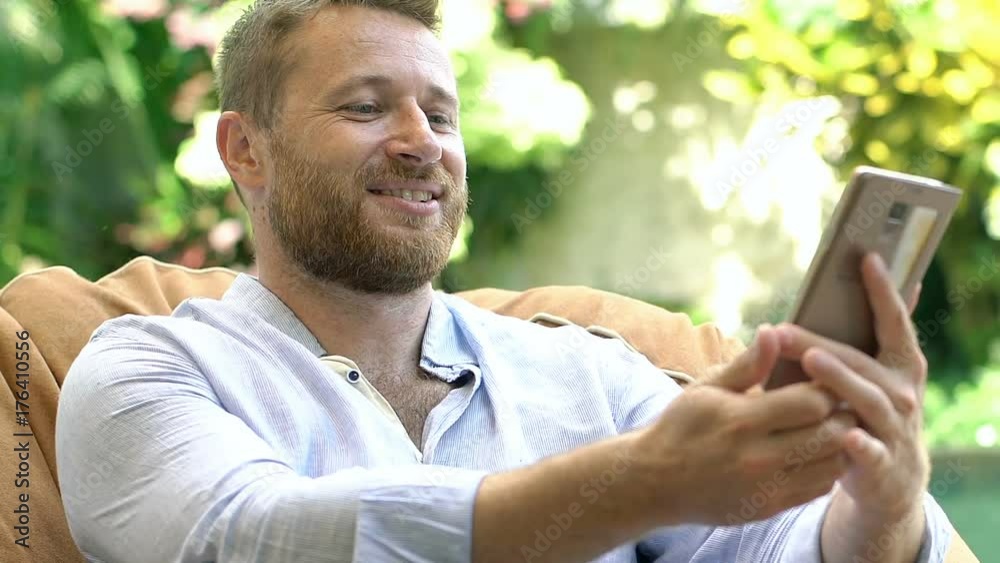 Handsome man relaxing on the bean bag chair and having a videocall on smartphone
Handsome man relaxing on the bean bag chair and having a videocall on smartphone