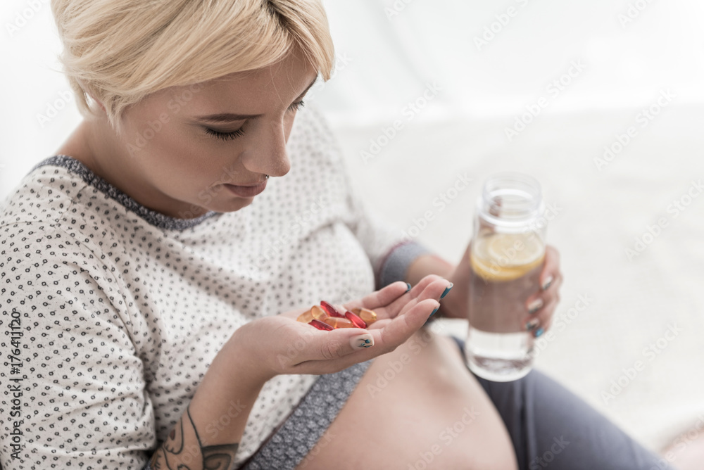 Fototapeta premium Gravid lady looking at means of cure