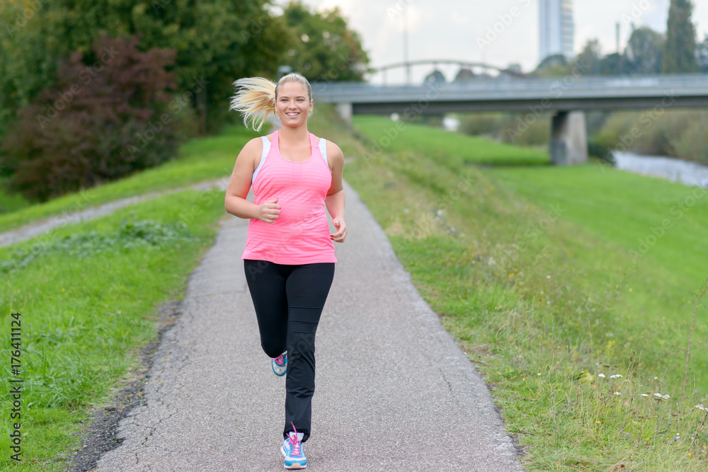 Blonde smiling woman running along river Blonde smiling woman running along river