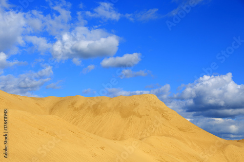 Kopalnia odkrywkowa, góra piasku na tle błękitnego nieba.