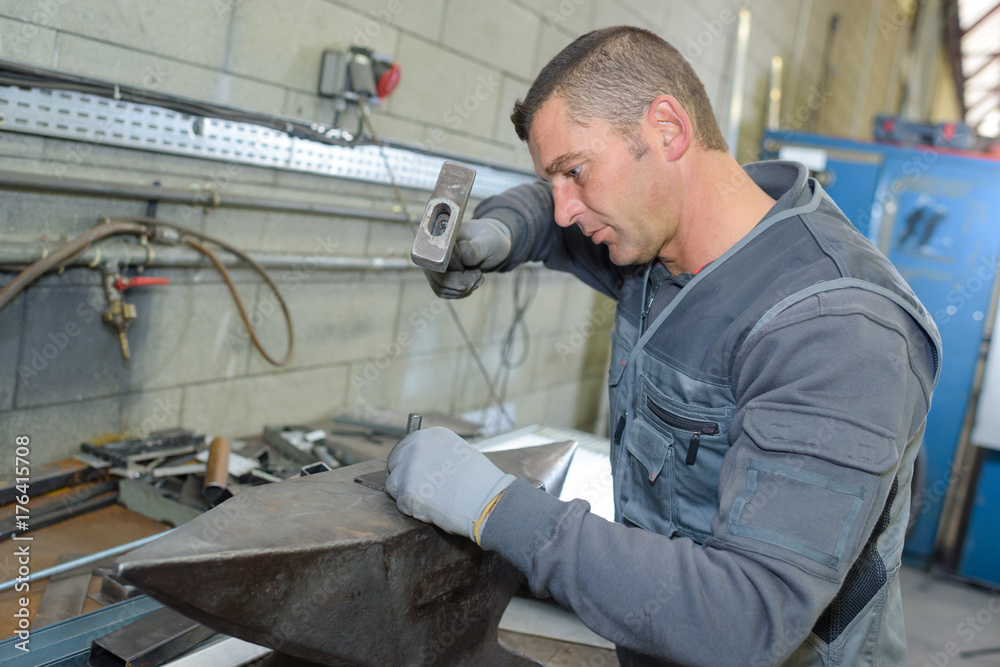 Workman hammering on to anvil